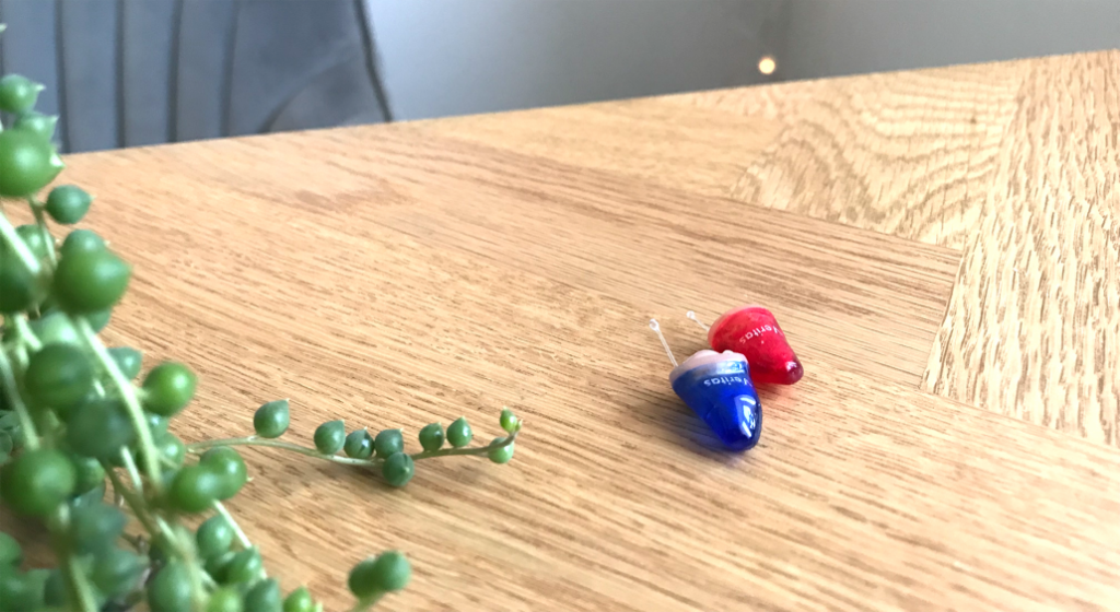 Veritas Hearing IIC Hearing Aids On A Wooden Table